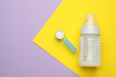 Photo of Feeding bottle with infant formula and powder on color background, flat lay. Space for text