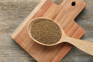 Photo of Spoon of celery seeds on wooden table, top view