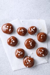 Photo of Tasty caramel candies and salt on light grey table, top view