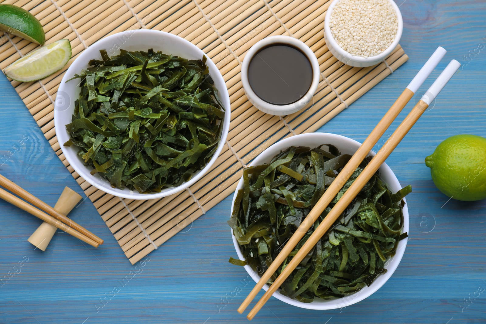 Photo of Fresh laminaria (kelp) seaweed served on light blue wooden table, flat lay