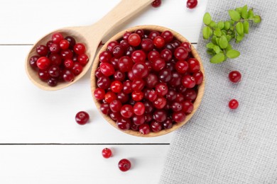 Photo of Fresh ripe cranberries and branches on white wooden table, top view