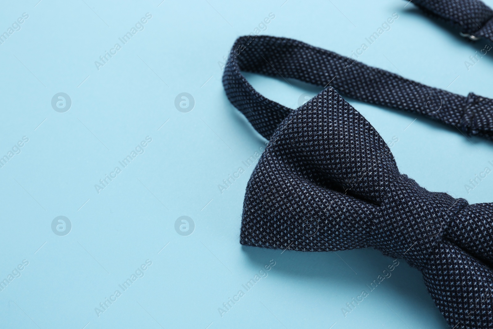 Photo of Stylish bow tie on light blue background, closeup. Space for text