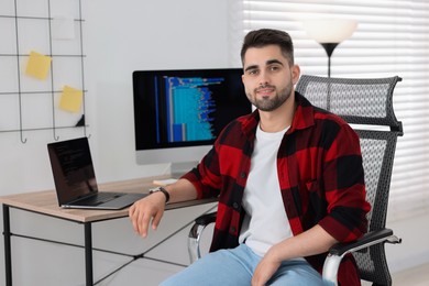 Photo of Happy young programmer working at desk in office