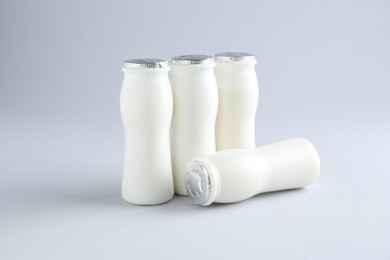 Photo of Tasty yogurt in bottles on light grey background