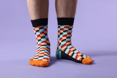 Photo of Man in stylish colorful socks on violet background, closeup