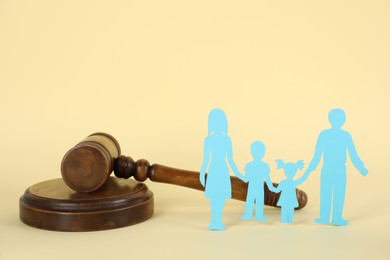 Paper family figure and wooden gavel on beige background. Child adoption concept