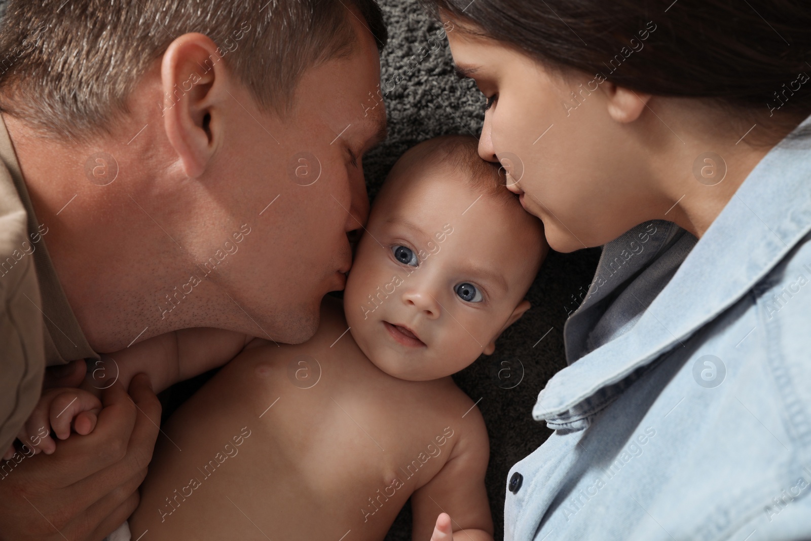 Photo of Happy family with their cute baby on floor, top view