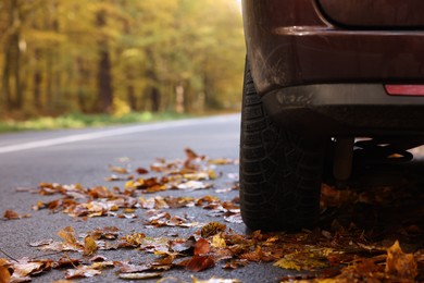 Photo of Modern car on asphalt road near autumn forest, closeup. Space for text