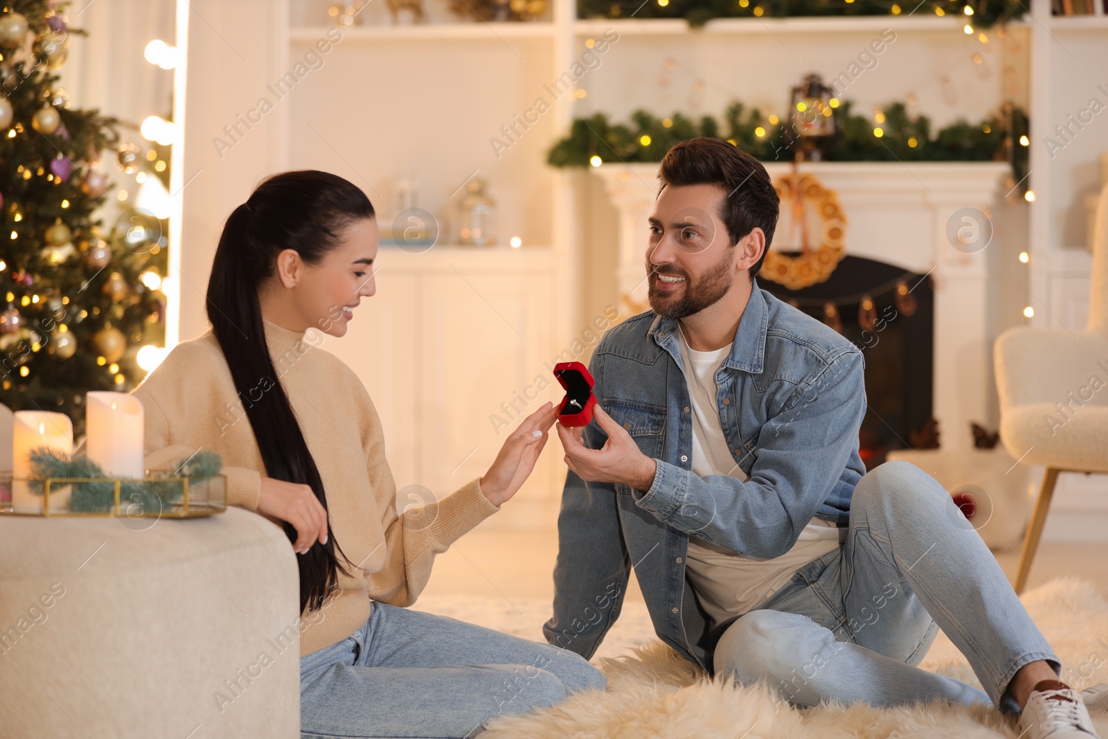 Photo of Man with engagement ring making proposal to his girlfriend at home on Christmas