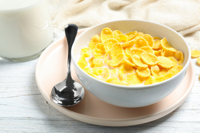 Tasty corn flakes with milk on white wooden table