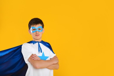 Photo of Teenage boy in superhero costume on yellow background. Space for text