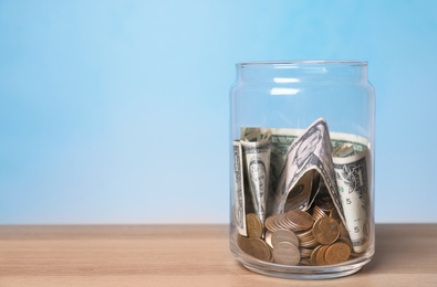 Donation jar with money on table against color background. Space for text