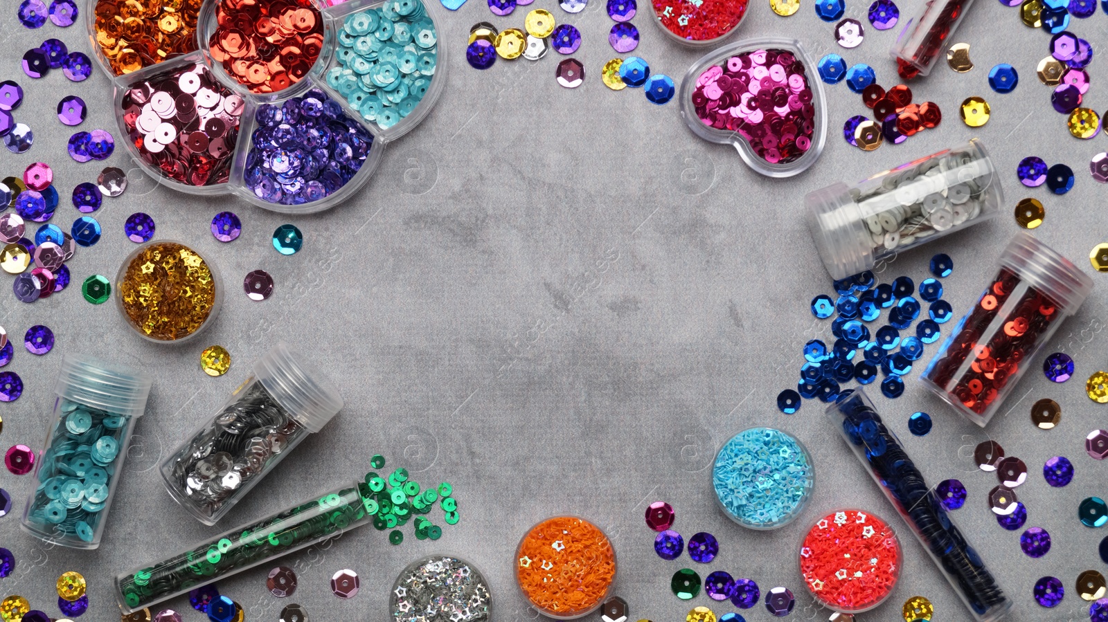 Photo of Frame of many different shiny colorful sequins on grey background, flat lay. Space for text
