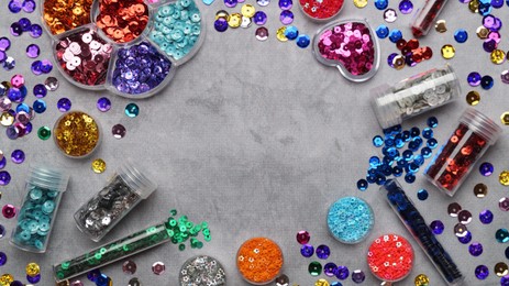Photo of Frame of many different shiny colorful sequins on grey background, flat lay. Space for text