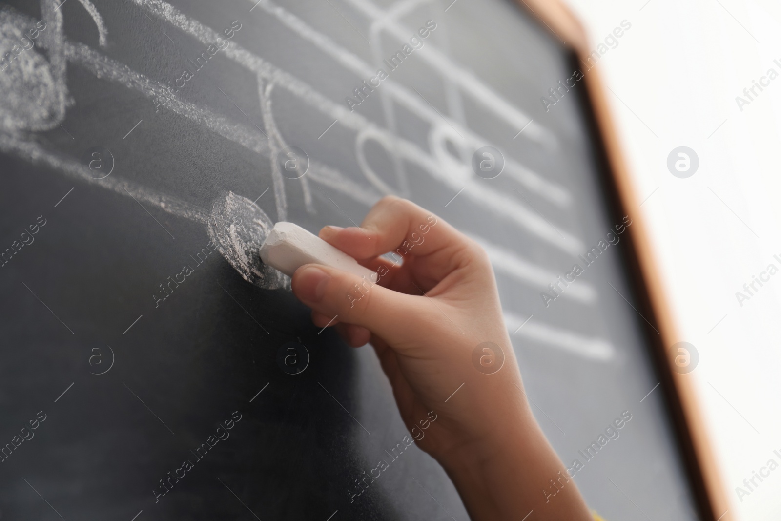 Photo of Child writing music notes on blackboard, closeup