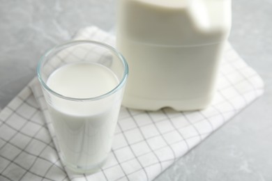 Photo of Glass of milk near gallon bottle on light table, closeup