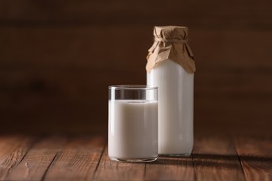 Photo of Tasty fresh milk in bottle and glass on wooden table