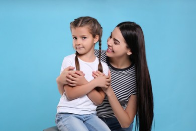 Happy woman with her cute daughter on light blue background. Mother's day celebration