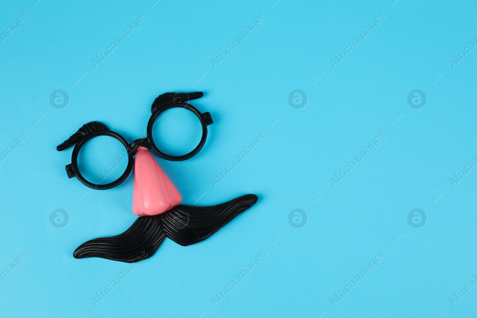 Photo of Funny mask with fake mustache, nose and glasses on light blue background, top view