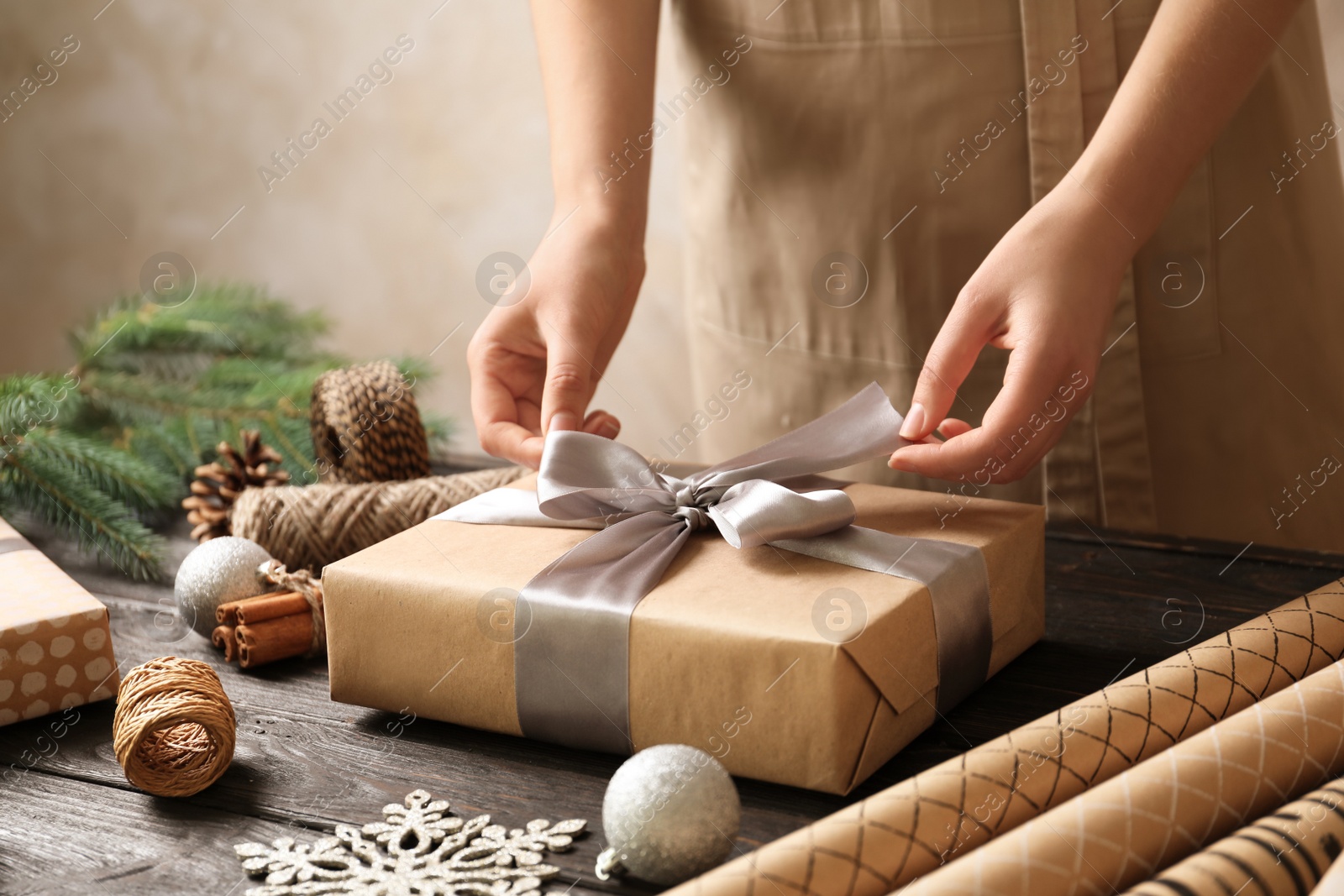 Photo of Woman wrapping Christmas gift at wooden table