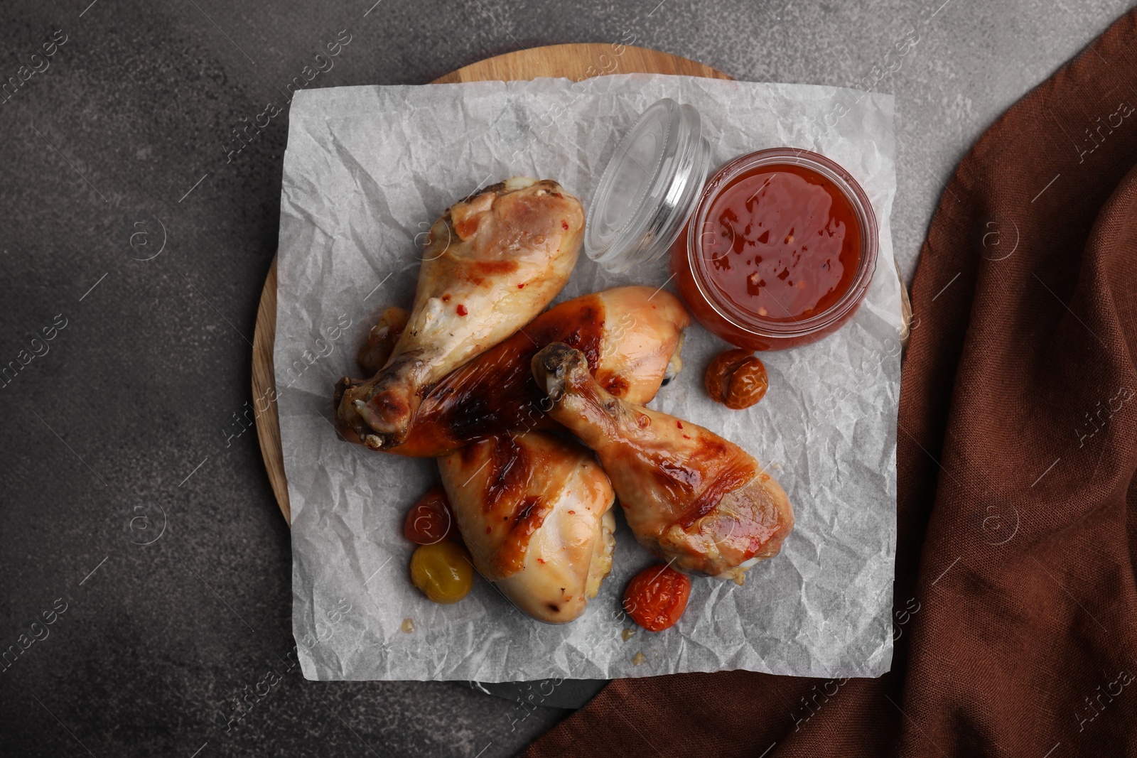 Photo of Delicious roasted chicken drumsticks, tomatoes and marinade on brown table, top view