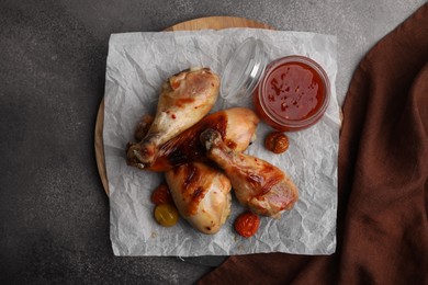 Photo of Delicious roasted chicken drumsticks, tomatoes and marinade on brown table, top view