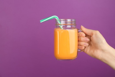 Photo of Woman holding mason jar with delicious smoothie on color background