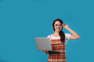 Young woman with laptop on blue background. Space for text