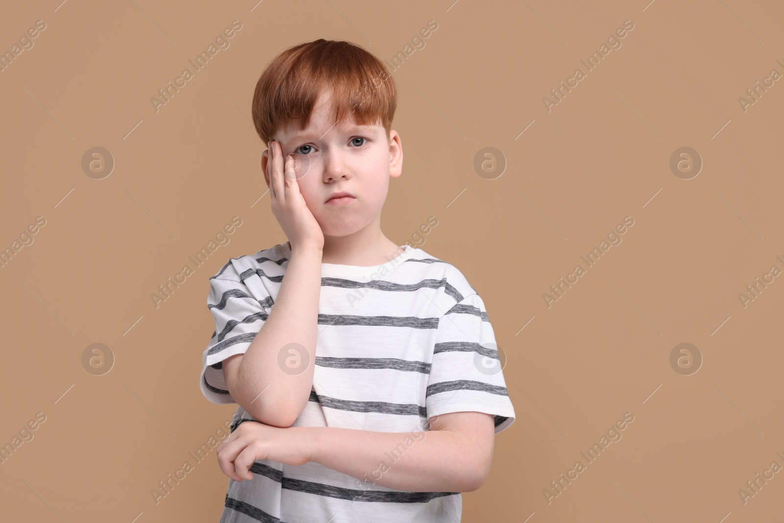 Photo of Portrait of sad little boy on beige background