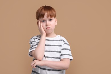 Photo of Portrait of sad little boy on beige background