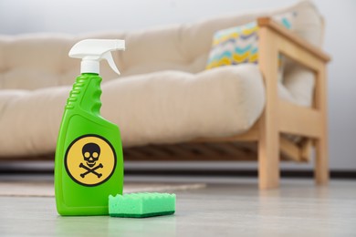 Bottle of toxic household chemical with warning sign and scouring sponge in room, space for text
