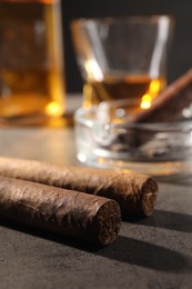 Photo of Cigars, ashtray and whiskey on grey table, closeup