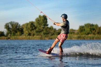 Photo of Teenage boy wakeboarding on river. Extreme water sport