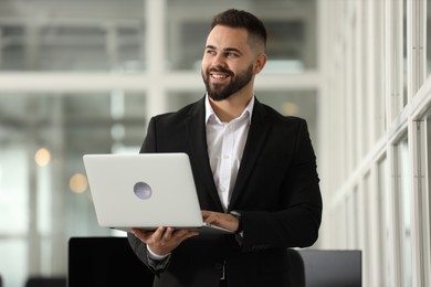 Photo of Portrait of smiling man with laptop in office. Lawyer, businessman, accountant or manager