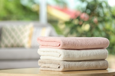 Photo of Stack of folded clean soft towels on table indoors
