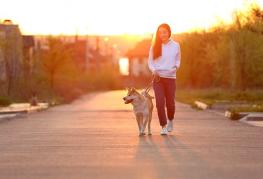 Photo of Young woman walking her adorable Akita Inu dog outdoors