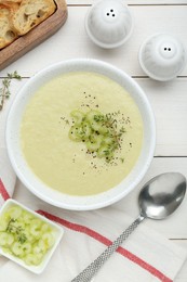 Photo of Bowl of delicious celery soup served on white wooden table, flat lay