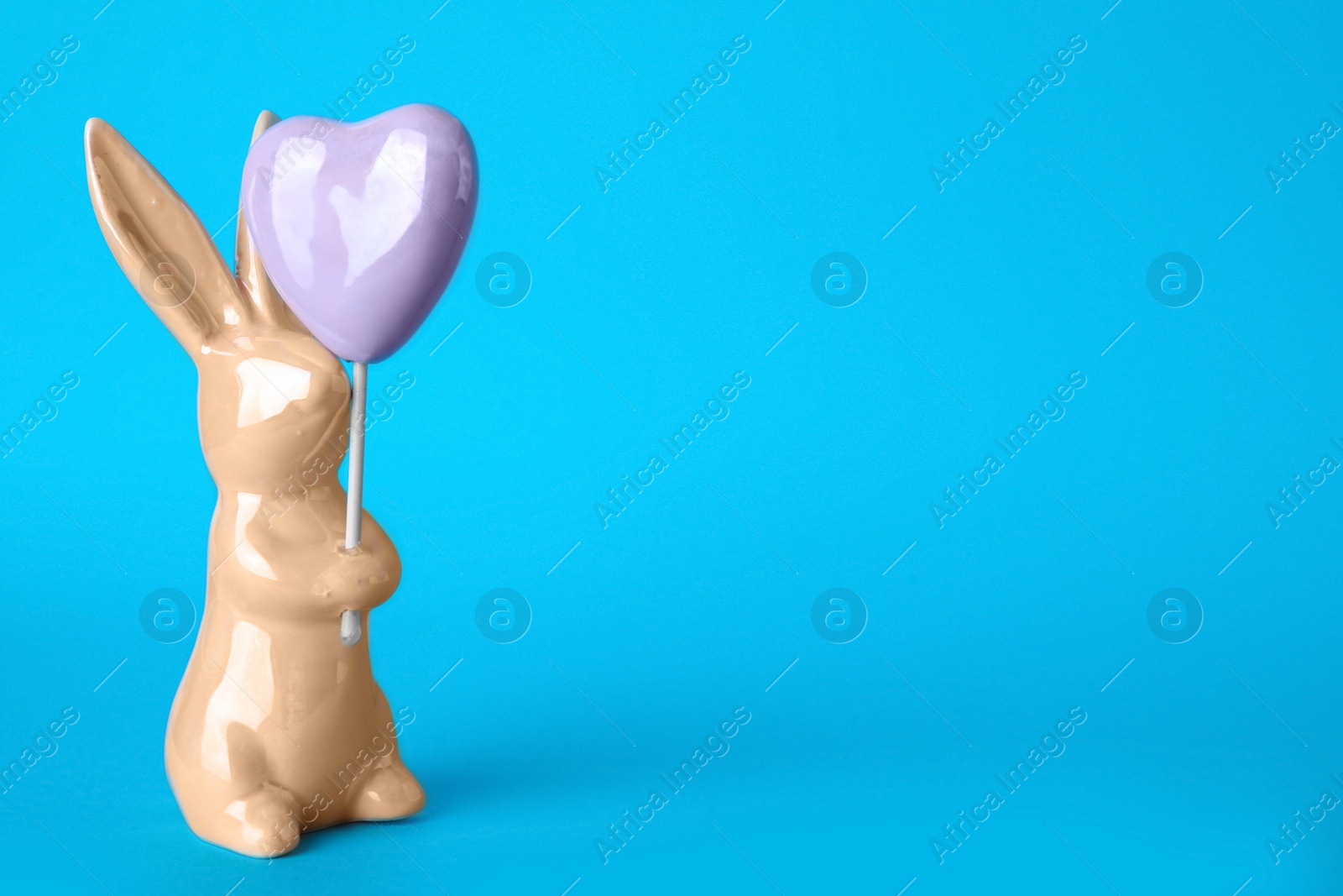 Photo of Bunny ceramic figure as Easter decor on blue background. Space for text