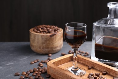 Photo of Coffee liqueur and beans on grey table, space for text