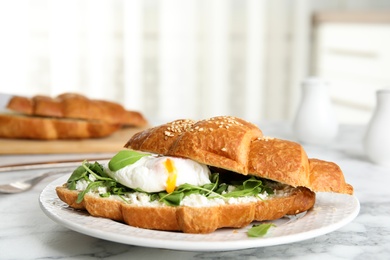 Delicious croissant with arugula and egg on white marble table