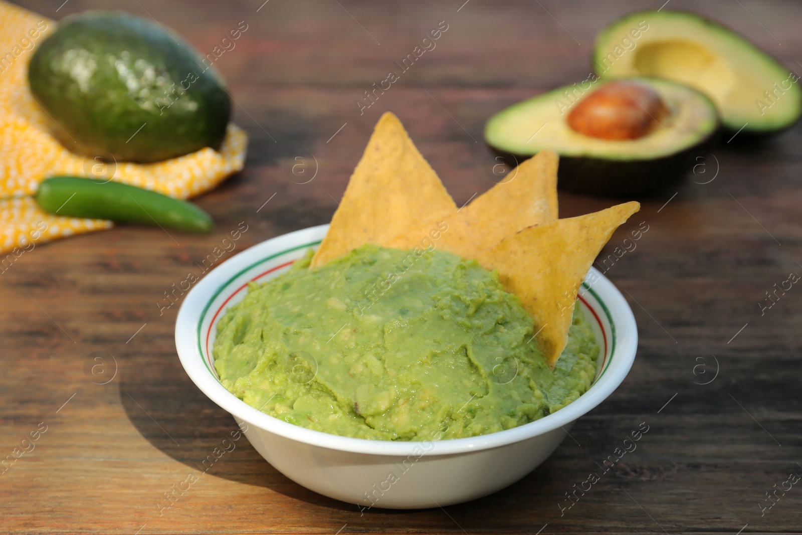 Photo of Delicious guacamole made of avocados with nachos on wooden table