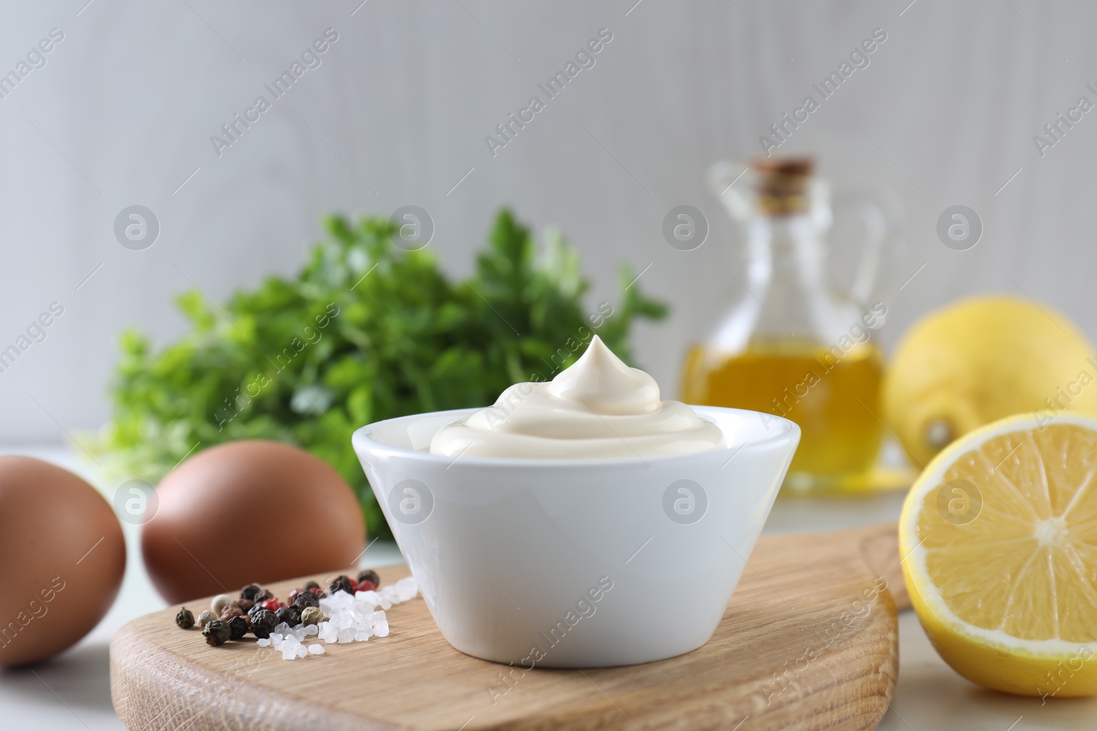 Photo of Tasty mayonnaise sauce in bowl, spices and ingredients on table, closeup