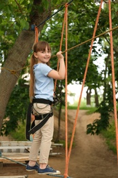 Photo of Little girl climbing in adventure park. Summer camp