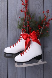 Photo of Pair of ice skates with Christmas decor hanging on grey wooden wall