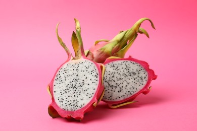 Photo of Delicious cut and whole dragon fruits (pitahaya) on pink background