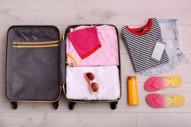 Packed suitcase on wooden background, top view