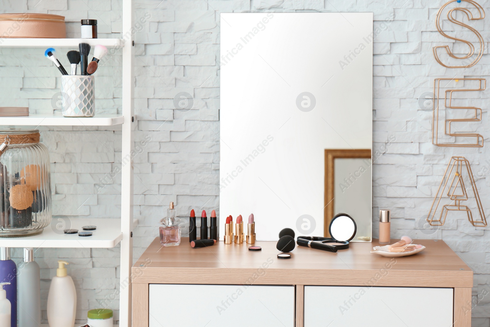 Photo of Decorative cosmetics and tools on dressing table near mirror in makeup room