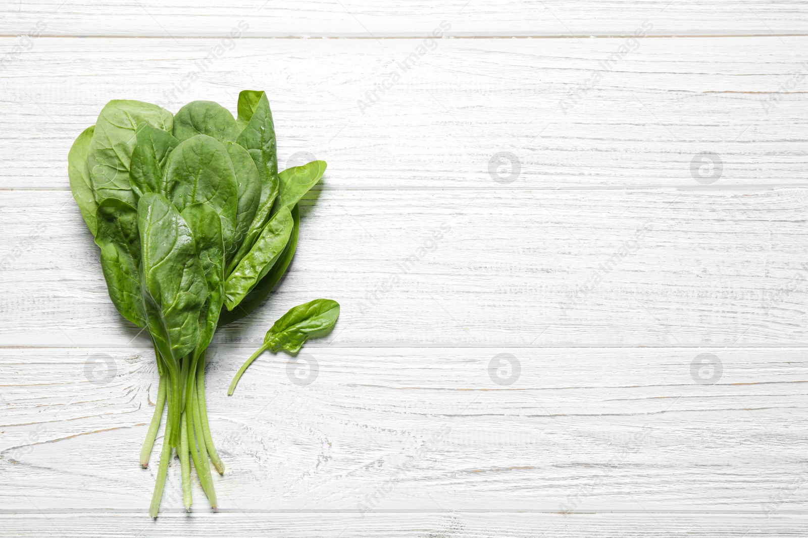 Photo of Fresh green healthy spinach on white wooden table, top view. Space for text