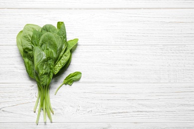 Photo of Fresh green healthy spinach on white wooden table, top view. Space for text