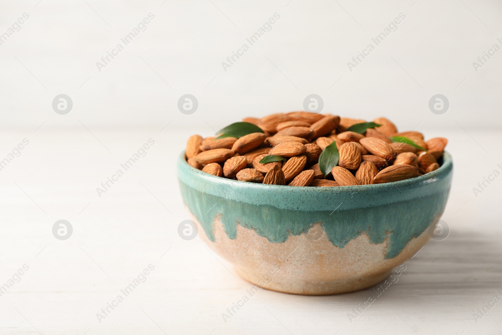 Photo of Tasty organic almond nuts in bowl on table